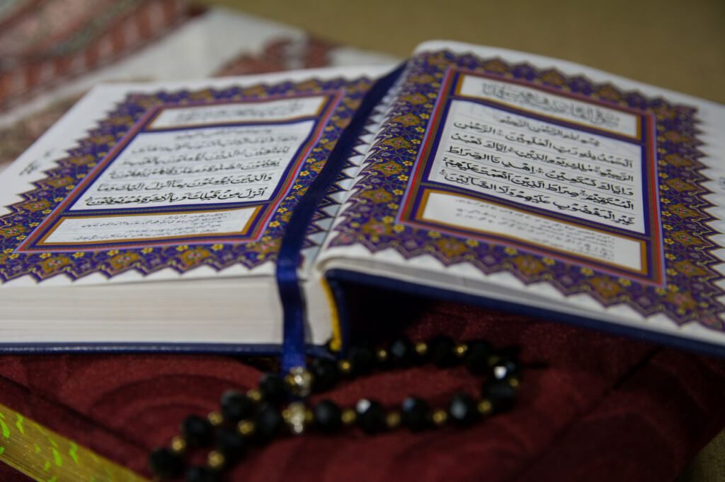Open Quran with prayer beads on a richly textured fabric, highlighting Arabic calligraphy and spirituality.