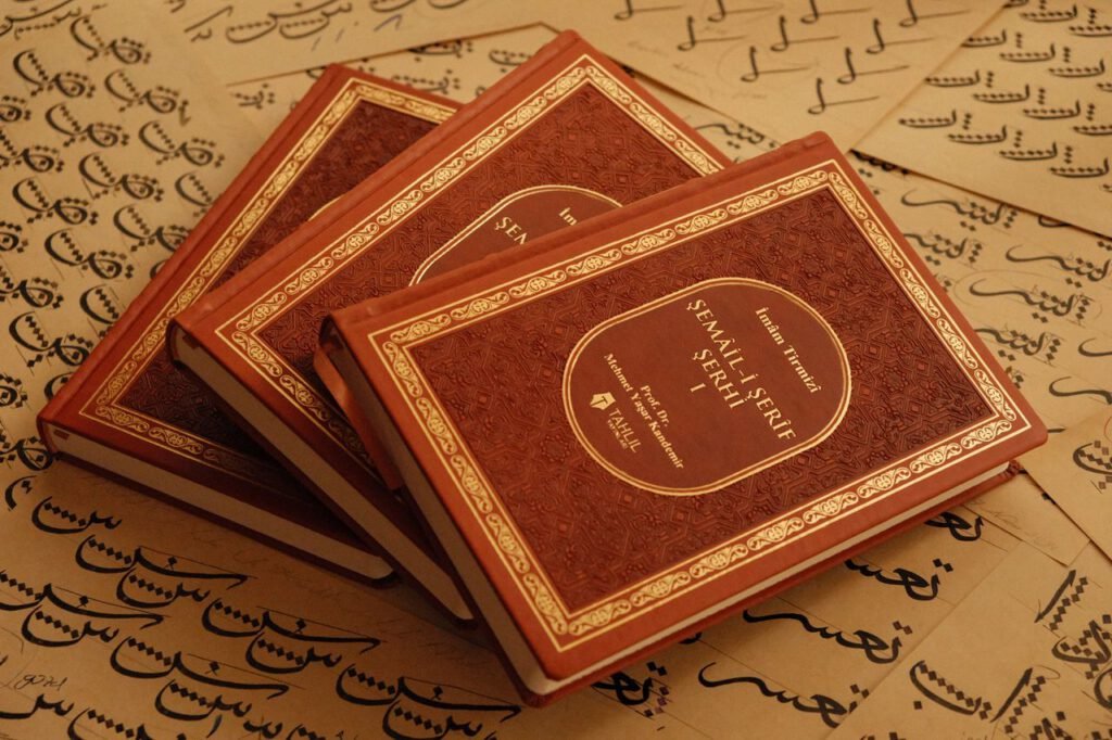 Elegant Islamic books placed on Arabic calligraphy sheets, showcasing artistic design.